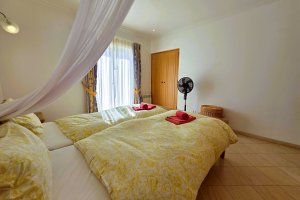 Schlafzimmer mit Doppelbett, Heizung und Ventilator mit Blick auf den Pool und Garten